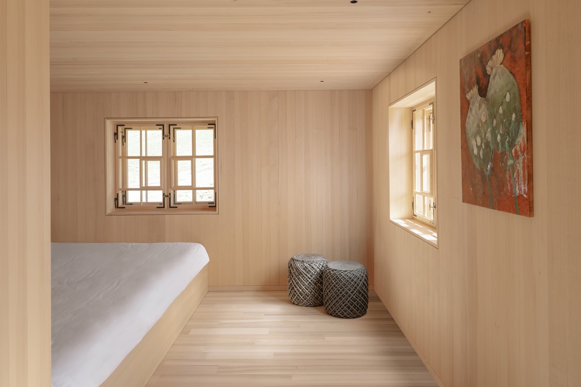 Im Inneren treffen klassisches Kassettentäfer und regionales Weißtannentäfer aufeinander und schaffen eine warme, ruhige Atmosphäre mit lokalem Charakter.