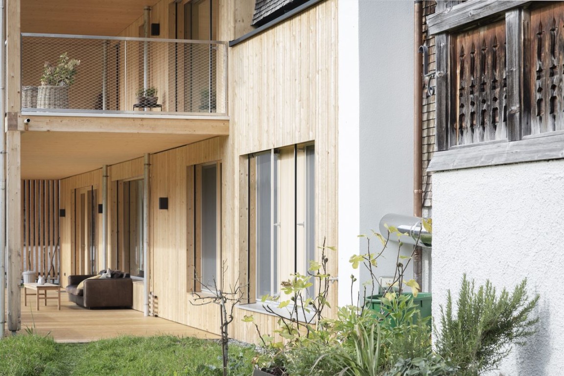 Moderne Holzfassade mit überdachter Terrasse und Gartenbereich