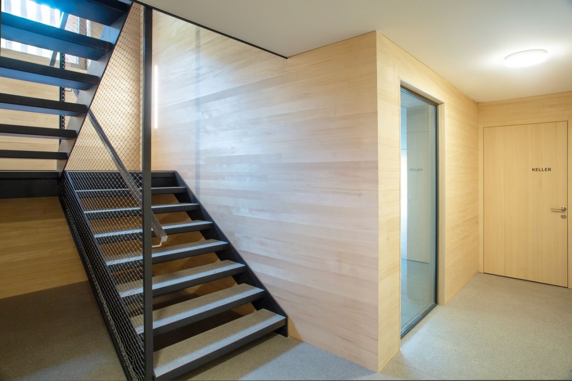 Helles Treppenhaus mit Holzverkleidung und Metalltreppe